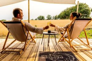 Ein Mann und eine Frau, die auf einem Deck auf Stühlen sitzen in der Unterkunft Lodges d'Exception avec jacuzzi privé I Montluçon I Auvergne in Prémilhat