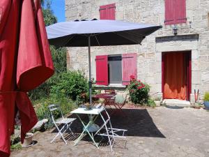 un tavolo e due sedie e un ombrellone e un tavolo e sedie di Maison nature Bien-être a Saint-Christophe-dʼAllier