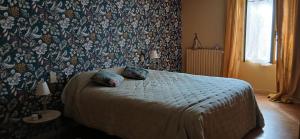una camera da letto con un letto con carta da parati floreale di Maison nature Bien-être a Saint-Christophe-dʼAllier Altre 3 foto