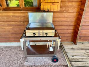 a grill on a cart in front of a wooden wall at Chalet Le Chappoix - SPA, terrasse et grand jardin in Granges-sur-Vologne