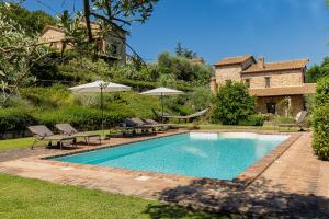 a swimming pool with chairs and umbrellas in a yard at Scappo in Umbria, casale della quiete in Montecchio