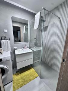 a bathroom with a shower and a sink and a washing machine at Nemesis in Podgorica