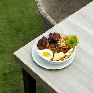 a bowl of food with an egg and vegetables on a table at Pelangi Hotel at Artotel Pelangi Park in Pasirkuda