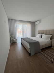 a bedroom with a large bed and a large window at Aver Beach Haven in Póvoa de Varzim