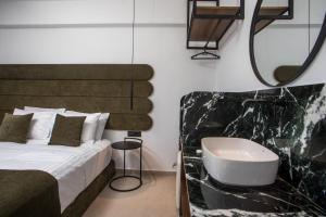 a bedroom with a bed with a sink and a mirror at Ermou 44 City Hotel in Faliraki
