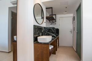 a bathroom with a sink and a mirror at Ermou 44 City Hotel in Faliraki
