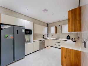 een keuken met roestvrijstalen koelkast en houten kasten bij Comfy apartment in AlKhobar in Al Khobar +27 foto's