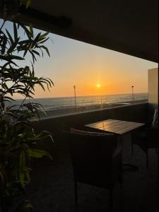 a sunset over the ocean with a table and chairs at Aver Beach Haven in Póvoa de Varzim