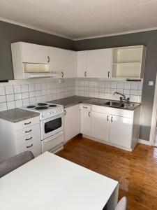a kitchen with white cabinets and a stove and a sink at Naturnära boende i Kosta in Kosta