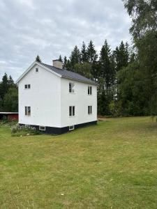 a large white house in a field with trees at Naturnära boende i Kosta in Kosta