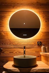 een badkamer met een wastafel met een ronde spiegel bij Appartement dans le Mercantour - accès PMR - in Saint-Étienne-de-Tinée