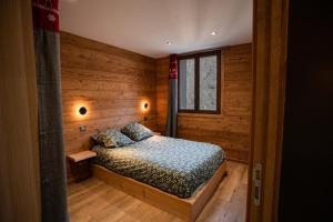 een slaapkamer met een bed in een houten kamer bij Appartement dans le Mercantour - accès PMR - in Saint-Étienne-de-Tinée
