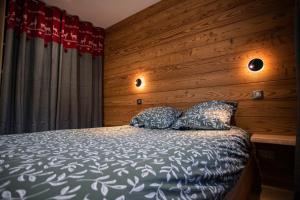 een slaapkamer met een bed met een houten muur bij Appartement dans le Mercantour - accès PMR - in Saint-Étienne-de-Tinée