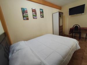 a bedroom with a white bed and a flat screen tv at Posada de Zarita in Chivay