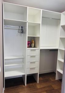 einen weißen begehbaren Kleiderschrank mit weißen Regalen in der Unterkunft Amarant Apart Hotel VB in Sumy