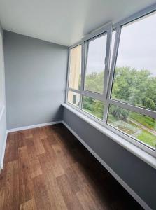 ein leeres Zimmer mit zwei großen Fenstern und Holzböden in der Unterkunft Amarant Apart Hotel VB in Sumy