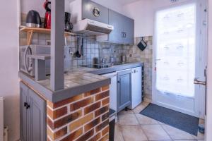 cocina con armarios azules y pared de ladrillo en La Canotière, en Saint-Georges-dʼOléron