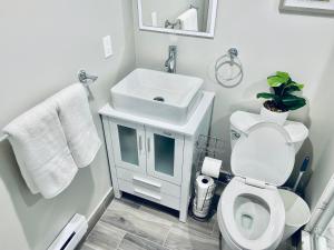 a white bathroom with a sink and a toilet at Bright, Stylish and Comfy Luxury Room With Workspace! in Haledon +15 photos