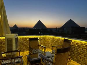 a balcony with chairs and a table and some pyramids at Pyramids Nun INN in Cairo