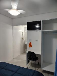 ein Schlafzimmer mit einem blauen Bett und einem schwarzen Stuhl in der Unterkunft Casa do Sol III in Peruíbe