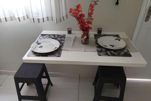 un tavolo bianco con due piatti e un vaso con fiori di kitnet Mobiliado apto 107 a Rio Branco Altre 8 foto