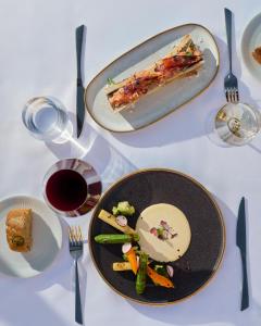 a table with two plates of food and a slice of pizza at Hotel Rural Palacio Haza de la Concepción in Malpartida de Plasencia