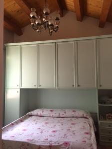 um quarto com uma cama com armários brancos e um lustre em Angolo Verde em Rometta Marea