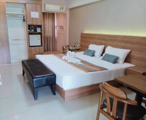 a bedroom with a large bed with a desk and a chair at Unity Hotel in Si Sa Ket