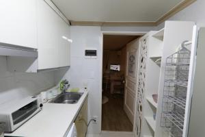 a small kitchen with white cabinets and a sink at GangNam Dream House in Seoul