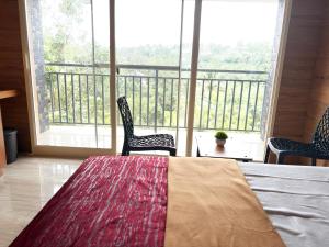 a room with a bed and two chairs and a balcony at Cozy meadows homestays in Anachal