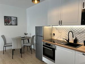 a kitchen with a sink and a table with chairs at Apartament 37 in Sosnowiec