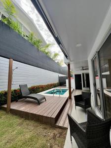 a wooden deck with chairs and a swimming pool at Modern Home with Private Pool - Selva Coral in Jaco - Just steps from the beach in Jacó