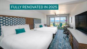 a hotel room with two beds and a television at Sea Edge Beachside Hotel in Parksville