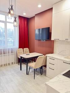 a kitchen with a table and chairs and a red wall at 2 room in the very center of the city near the mega park and walking distance to the Arbat in Almaty