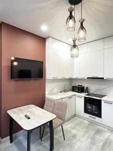 a kitchen with white cabinets and a table with chairs at 2 room in the very center of the city near the mega park and walking distance to the Arbat in Almaty