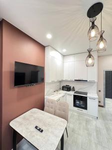 a kitchen with a table and a tv on a wall at 2 room in the very center of the city near the mega park and walking distance to the Arbat in Almaty +20 photos