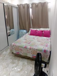 a bedroom with a bed with pink pillows and a mirror at Recanto das Águias in Maricá