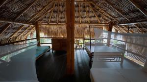 a straw hut with two beds and a desk in it at Aguarinwa Hostel in Palomino