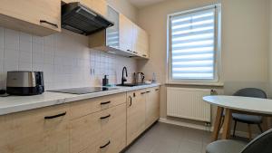 a kitchen with wooden cabinets and a table and a window at Ursus Pleasant Apartment by BookingHost in Warsaw +8 photos