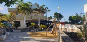 a playground in front of a building with palm trees at La Caleta Luxury Seaside Villa with 3 Bedrooms and Private Pool in Adeje