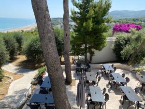 an outdoor patio with tables and trees and the ocean at Villaggio Hotel Ripa in Rodi Garganico