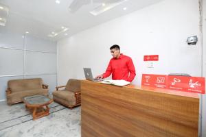 a man standing at a counter with a laptop at Hotel O The Nest in Sohāna