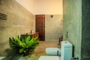 a bathroom with a toilet and a plant in it at Rukmale Gedara Bungalow in Pannipitiya +41 photos