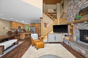 a living room with a stone fireplace and a tv at Gorgeous Executive Lutsen Townhome - Ski-in Ski-out, Pool, Hot Tub, Hiking, Biking, campfires and more! in Lutsen
