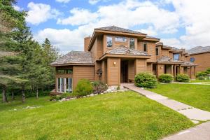 Una casa con un césped verde delante de ella. en Gorgeous Executive Lutsen Townhome - Ski-in Ski-out, Pool, Hot Tub, Hiking, Biking, campfires and more!, en Lutsen