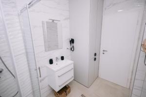 un bagno bianco con lavandino e doccia di Stan na dan "Aparté" Brčko a Brčko Altre 15 foto