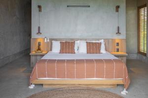 a bedroom with a large bed with brown and white pillows at Casa Miguana - Chiwiro in San Agustinillo +19 photos
