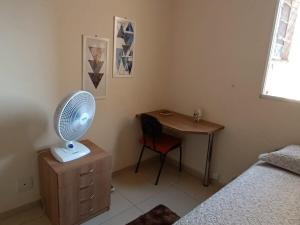 Schlafzimmer mit einem Schreibtisch und einem Tisch mit einem Ventilator in der Unterkunft Quarto apê completo , Centro, Damhas e Rodoviária , localização privilegiada in Sao Jose do Rio Preto