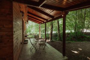a patio with chairs and tables under a wooden roof at Cheerful Forest Cabin with Hot Tub! 