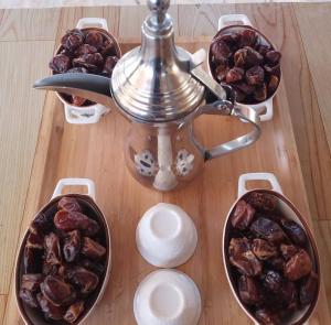 a table with bowls of dates and a tea kettle at Star line for Desert Camping in Badīyah